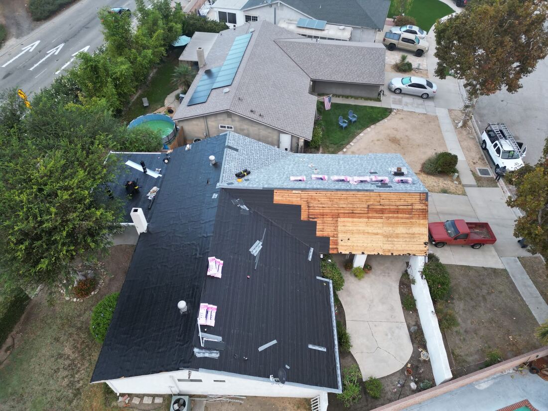 Aerial view of a full roof tear-off and shingle replacement in progress on a Southern California home