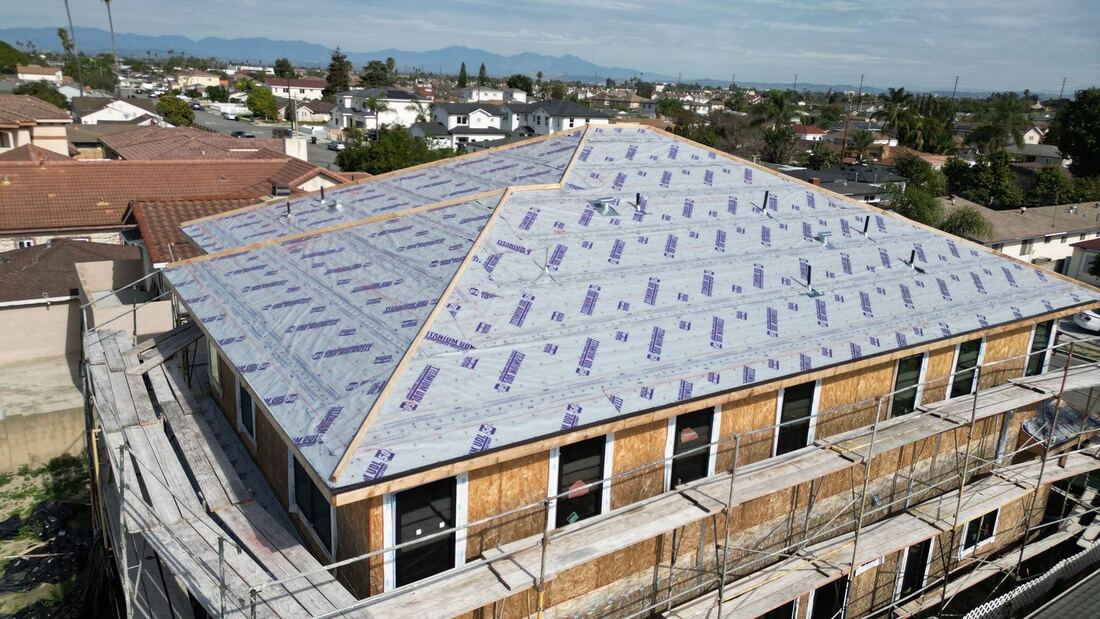 Aerial view of synthetic underlayment installed on a new construction roof