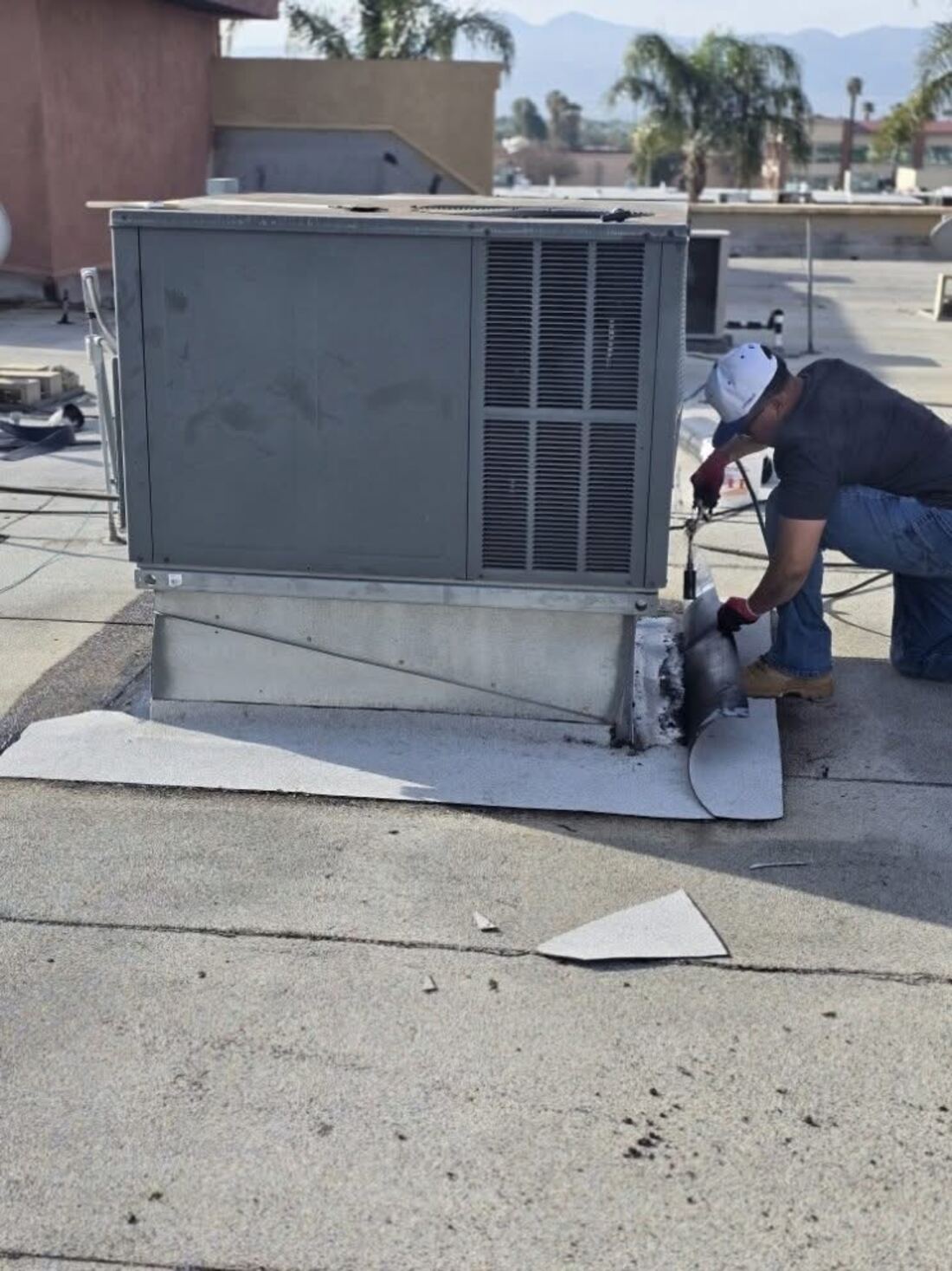 Roofer repairing HVAC curb flashing on a flat roof