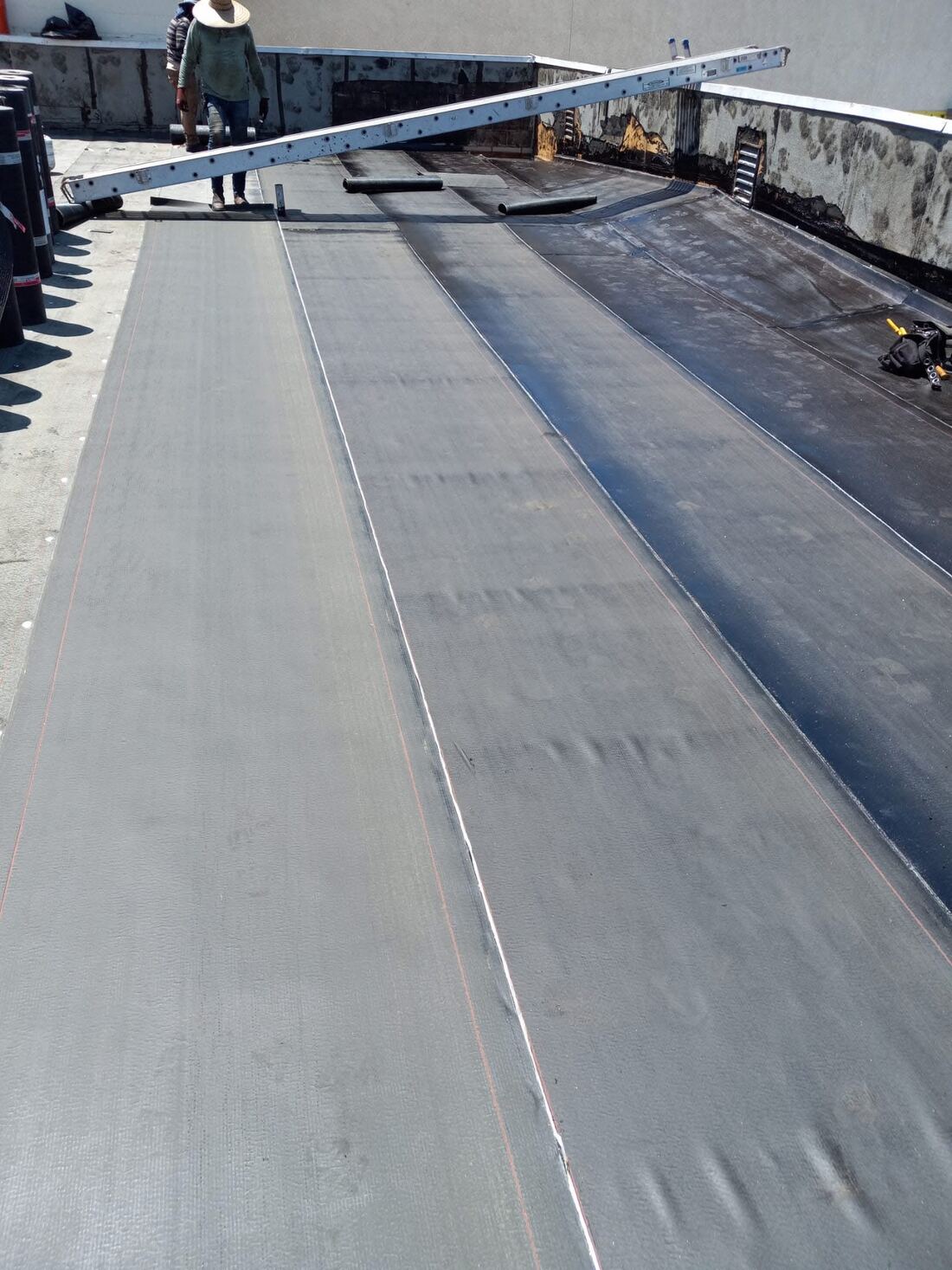 Torch-down modified bitumen roofing installation on a flat roof